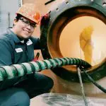 Environmental technician in action assisting with cleaning an industrial chemical tank.